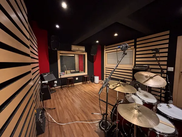 Sala de gravação do Estúdio B2 em ângulo amplo, com a bateria e os painéis acústicos