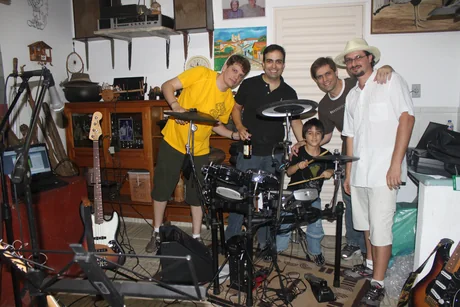 Rafael Baino criança, tocando bateria em casa, cercado pela banda B2, em dezembro de 2010